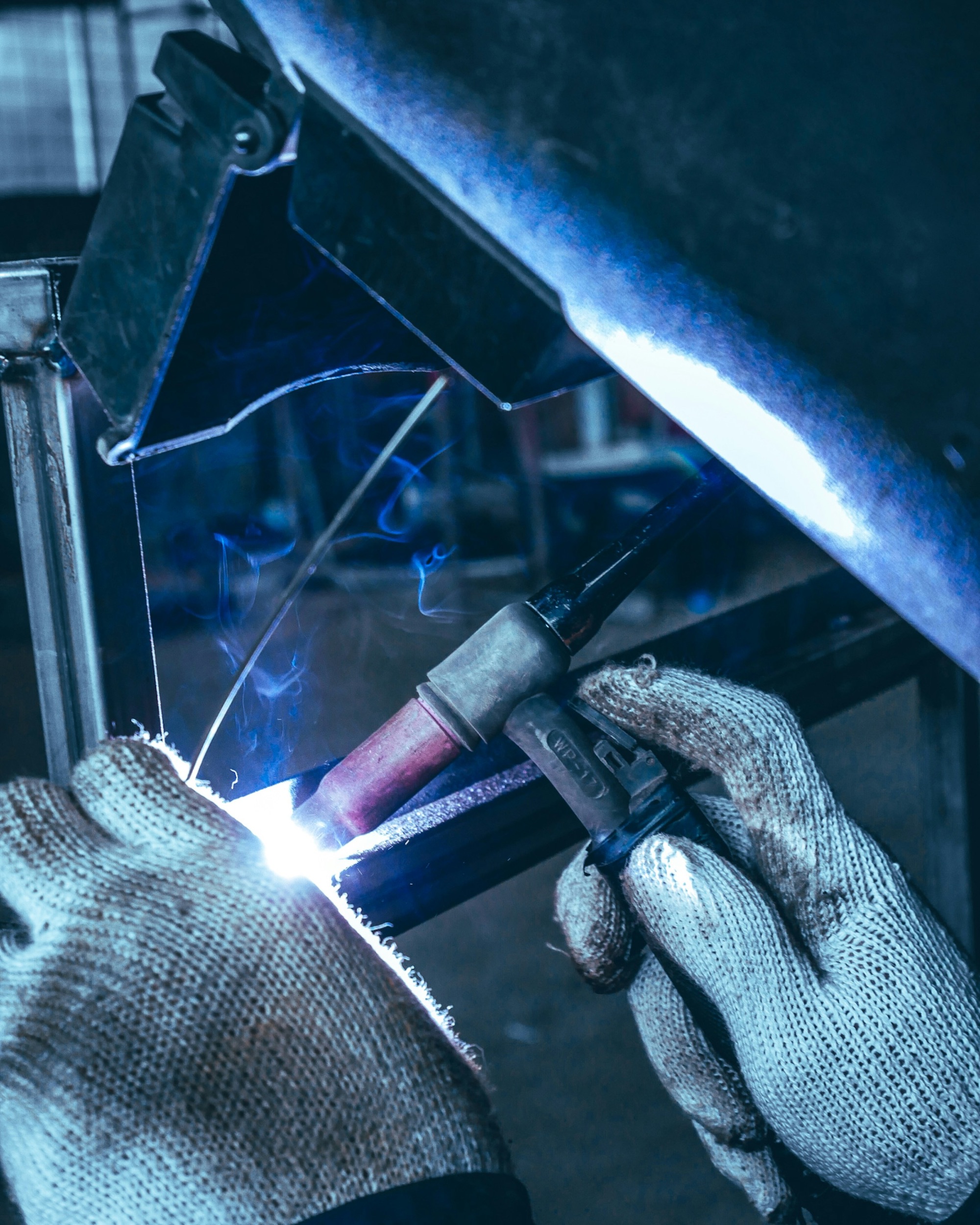 Welder working on a piece of metal in a factory setting