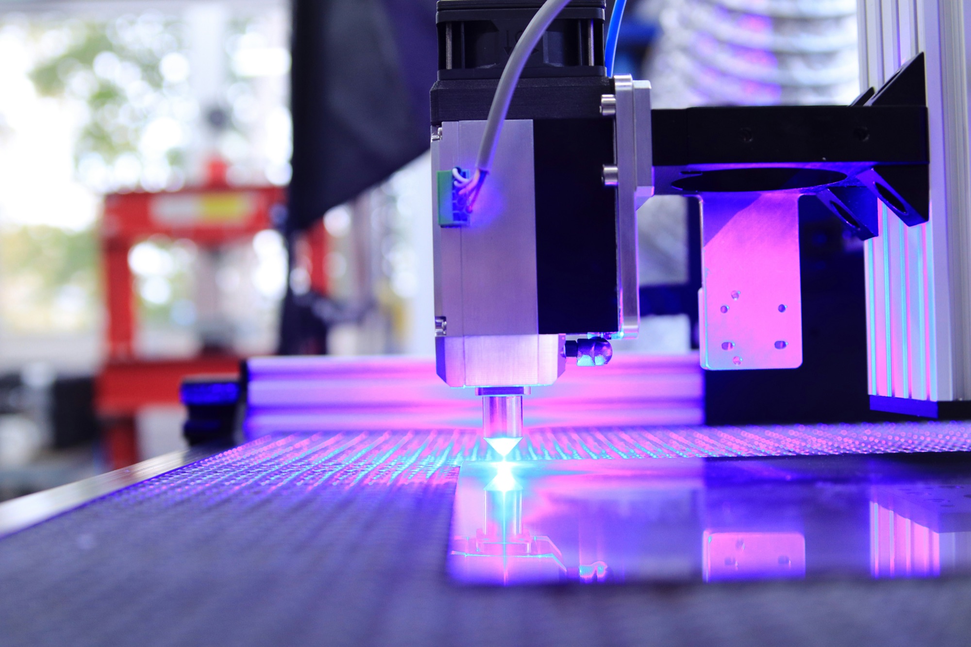 Laser cutting head over a metal workpiece, purple laser glow