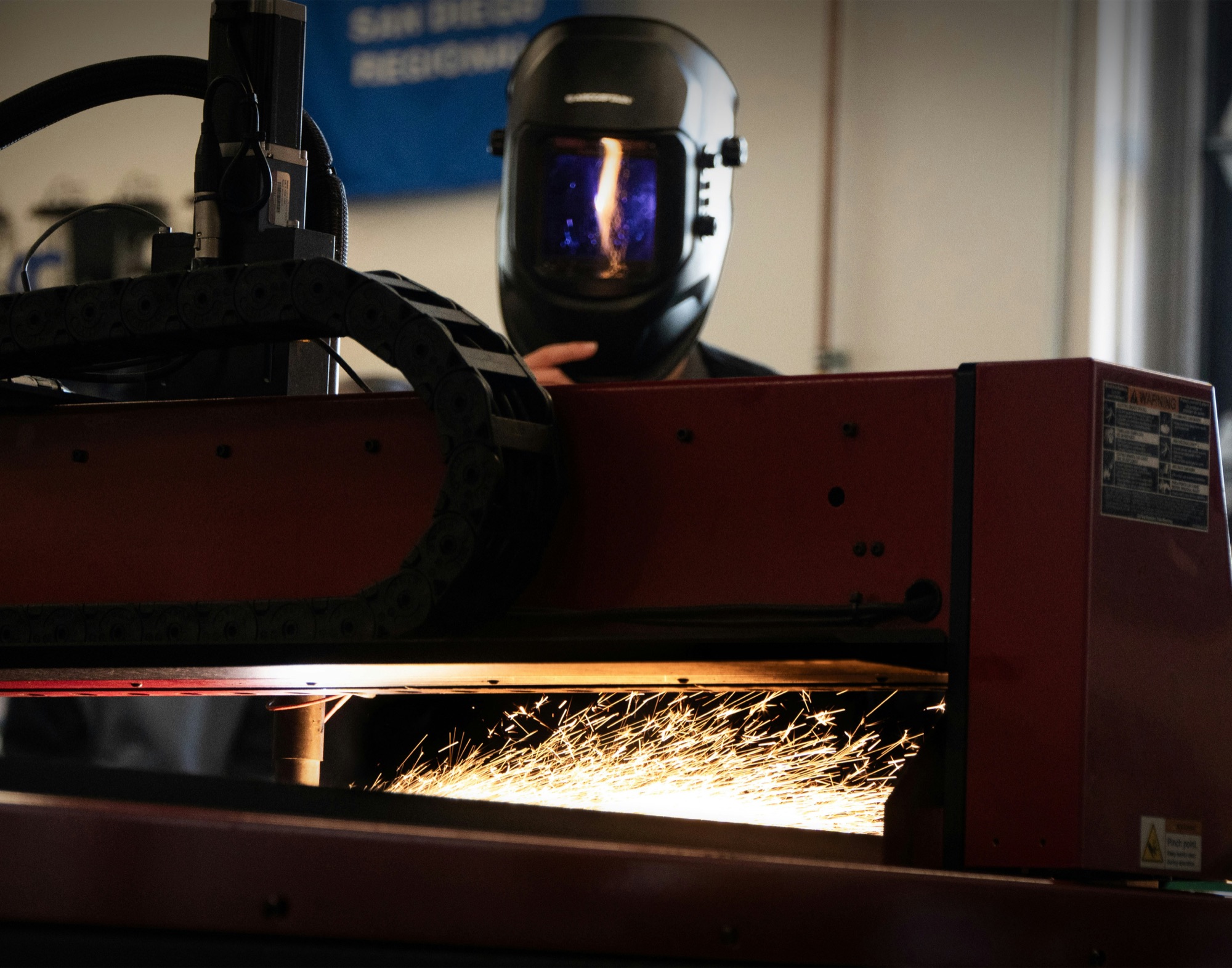 Operator in a welding helmet working on a metal piece