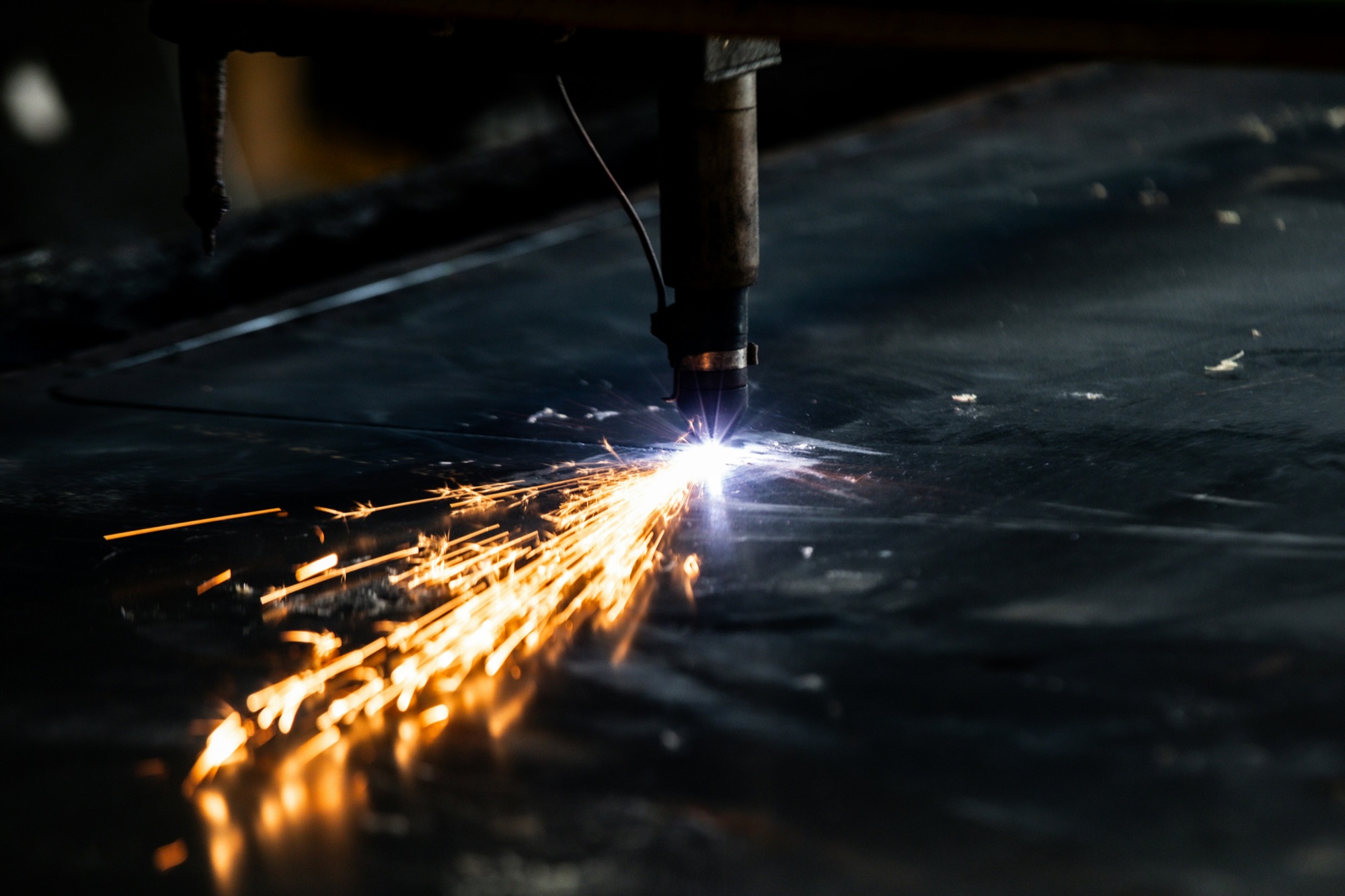 Welder cutting a piece of metal with bright sparks flying